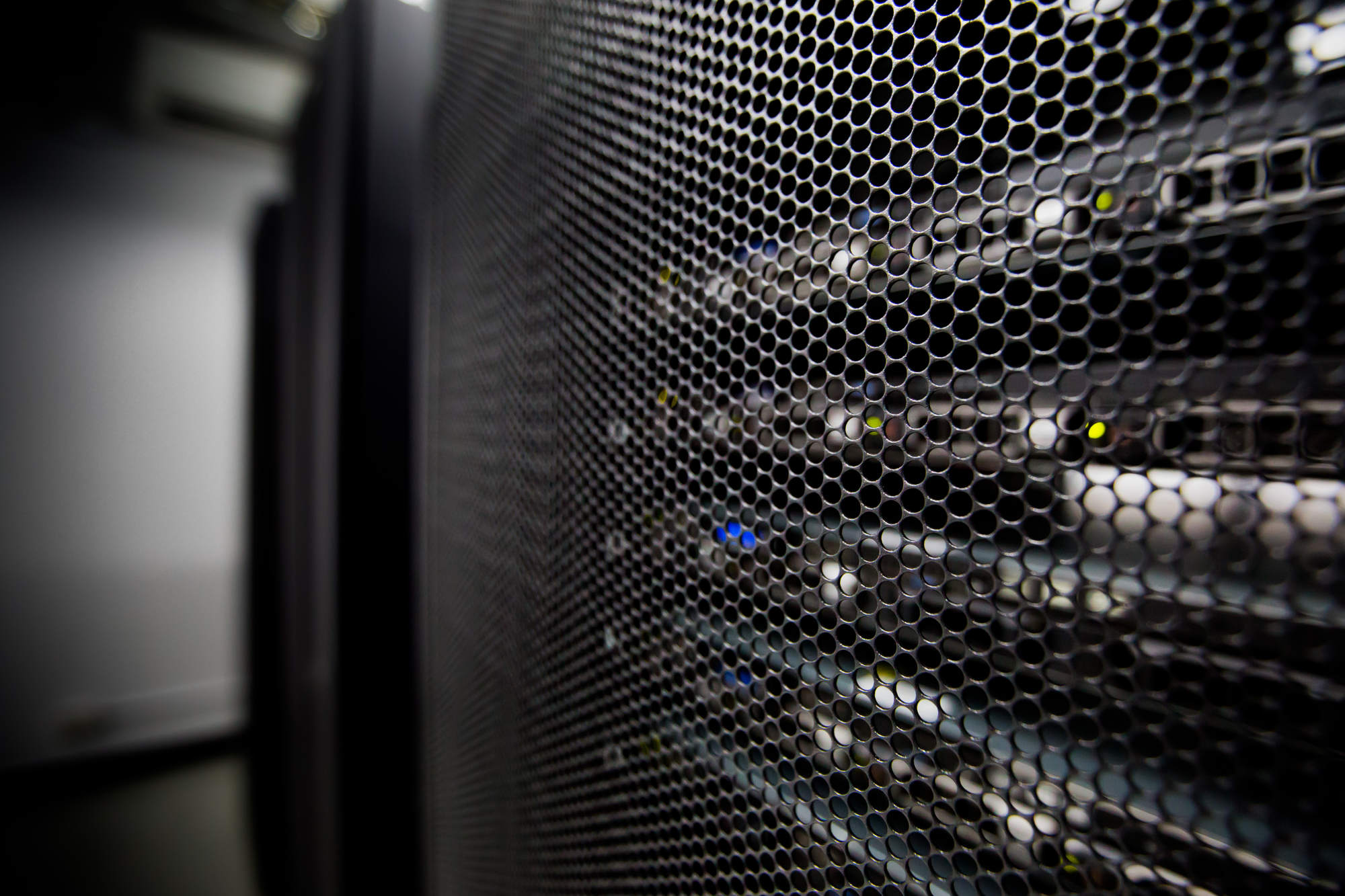Close up of the perforated front panels of rack mounted servers with status indicator lights